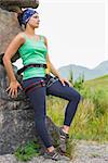 Attractive female rock climber leaning on rock face in the countryside