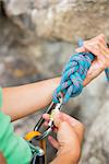 Female rock climber adjusting her harness by the rock face