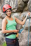 Pretty rock climber about to start her climb by rock face