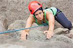 Determined girl climbing rock face looking at camera