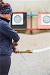 Brunette preparing her bow and arrow at the archery range