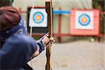Brunette about to shoot arrow at the archery range