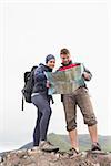 Couple standing on a rock reading map on a hiking trip