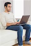 Focused handsome man using his tablet computer in cosy bright living room