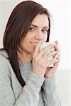 Smiling brunette drinking a cup of coffee at home