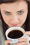 Smiling brunette drinking a cup of coffee looking at camera
