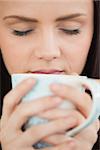 Brunette holding a cup of coffee eyes closed