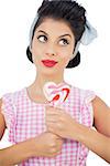 Pensive black hair model holding a heart shaped lollipop on white background