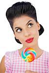 Wondering black hair model holding a colored lollipop on white background