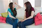 Two friends chatting on the sofa at home in living room