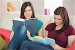Two girls reading books on the couch in sitting room at home