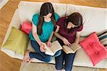 Two friends reading books on the couch in sitting room at home