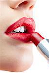 Extreme close up on gorgeous model on white background applying red lipstick
