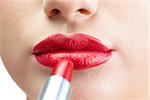 Extreme close up on beautiful red lips being made up on white background