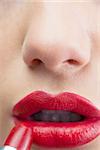 Extreme close up on sensual red lips being made up on white background