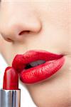 Extreme close up on gorgeous red lips being made up on white background