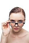 Unsmiling clean model looking over her classy glasses on white background