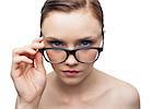 Serious clean model looking over her classy glasses on white background
