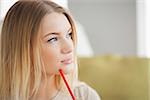 Thoughtful woman holding red pen at home in living room