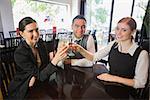 Business team celebrating a success with champagne in restaurant looking at camera