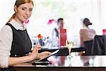 Businesswoman using tablet and looking at camera in a restaurant