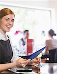 Happy businesswoman holding tablet and wine glass looking at camera in a restaurant