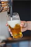 Hand holding glass filling beer pouring from a beer tap