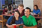 Two men and woman laughing in a cafe