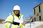 Portrait of female with blueprint and digital tablet on construction site