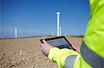 Project manager using digital tablet in front of wind farm