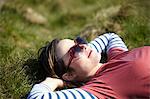 Young woman wearing heart shape sunglasses lying on grass