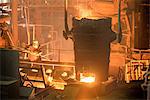 Elevated view of steel worker and molten bucket in steel foundry