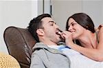 Young couple lying on sofa sharing popcorn