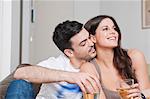 Young couple sitting on sofa sharing glass of wine