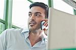 Close up of young male office worker talking on mobile phone