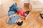 Young couple lying on floor amongst cardboard boxes