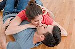 Young couple lying together on wooden floor