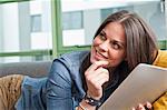 Close up of young woman lying on sofa holding digital tablet