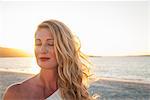 Blond woman with eyes closed on beach at dusk, Cape Town, South Africa