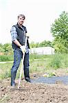 Portrait of organic farmer raking soil