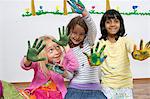 Three girls kneeling on floor with painted hands