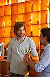 Two men standing at bar with bottles of beer