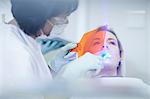 Female dentist applying ultraviolet light to patients teeth