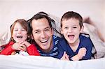Father and two young children posing under duvet