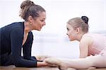 Teacher and young ballerina practicing floor stretch