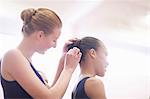 Teenage ballerina helping friend with hair