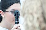 Female optician looking through ophthalmoscope