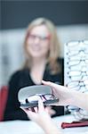 Shop assistant showing customer glasses in opticians shop