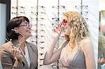 Two women trying on eyeglasses in opticians shop