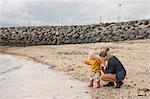 Mother and toddler crouching at waters edge